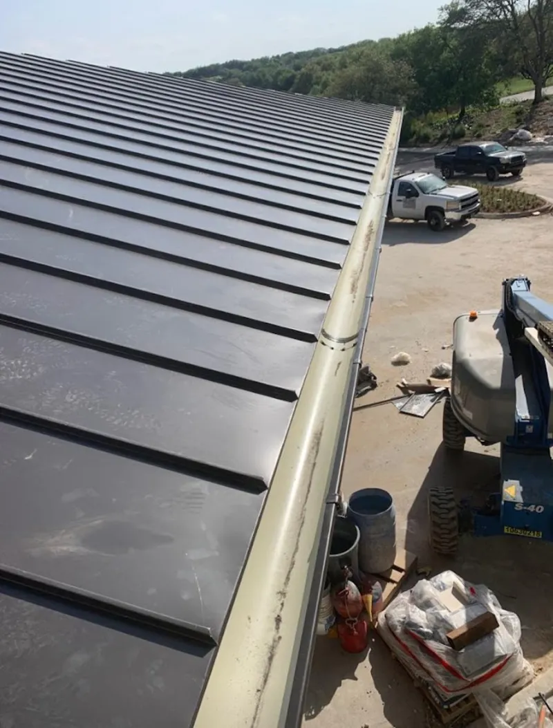 Standing seam panel and gutter detail on a metal roofing jobsite in Acton